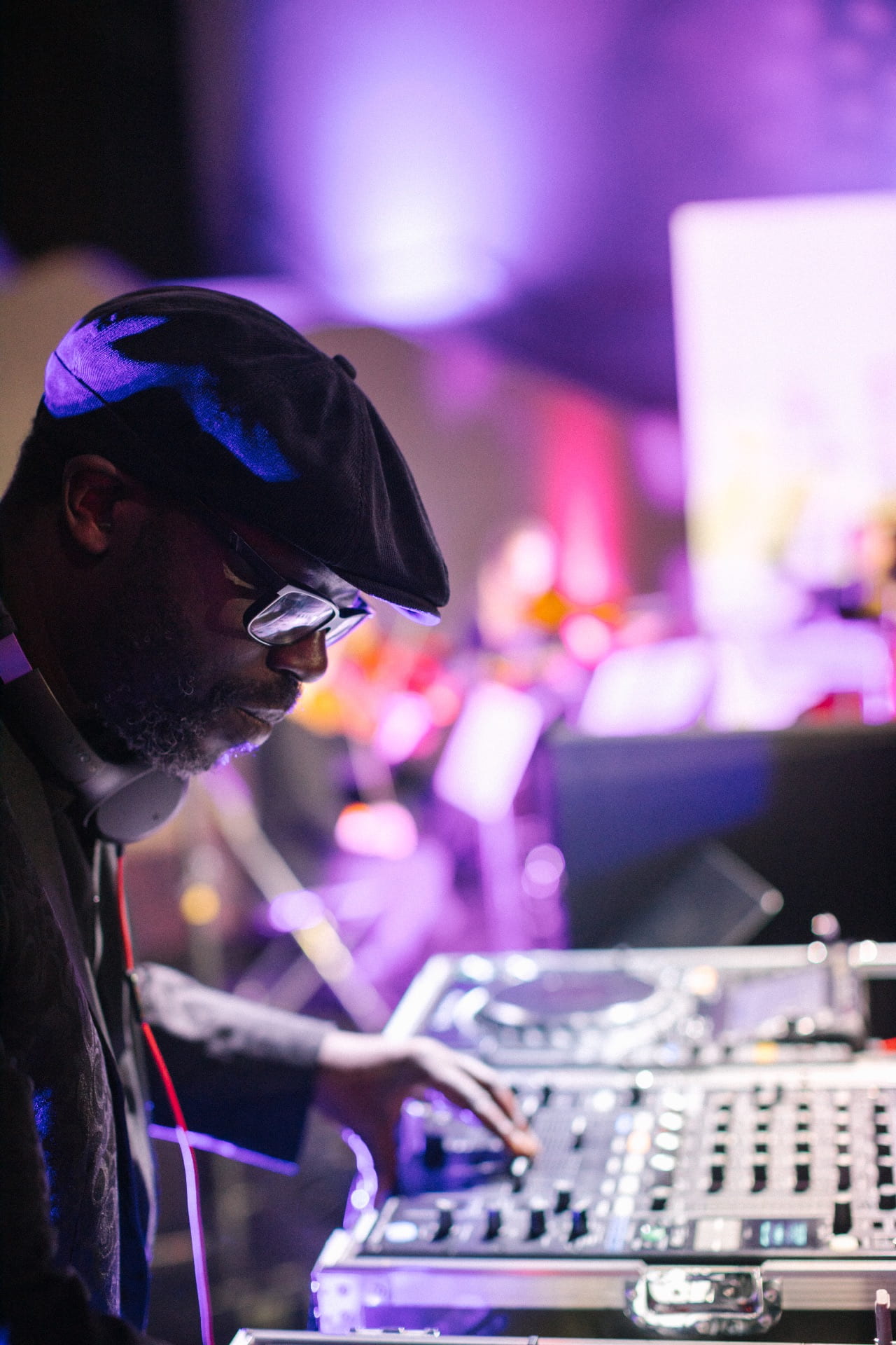 image of Peter adjure playing music from DJ deck with purple lighting around him